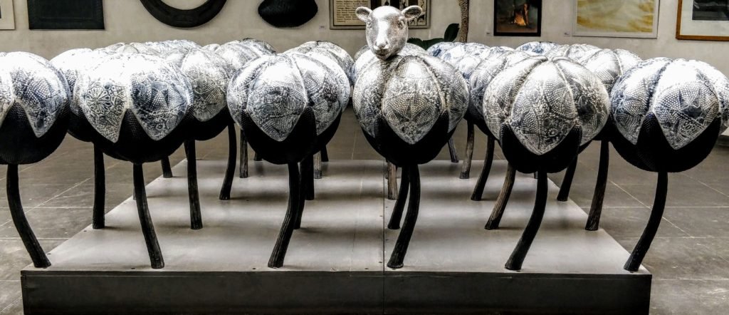 Art installation at Museum of Goa showing white cotton ball sculptures with one featuring a sheep's head, exploring themes of textile industry and agriculture