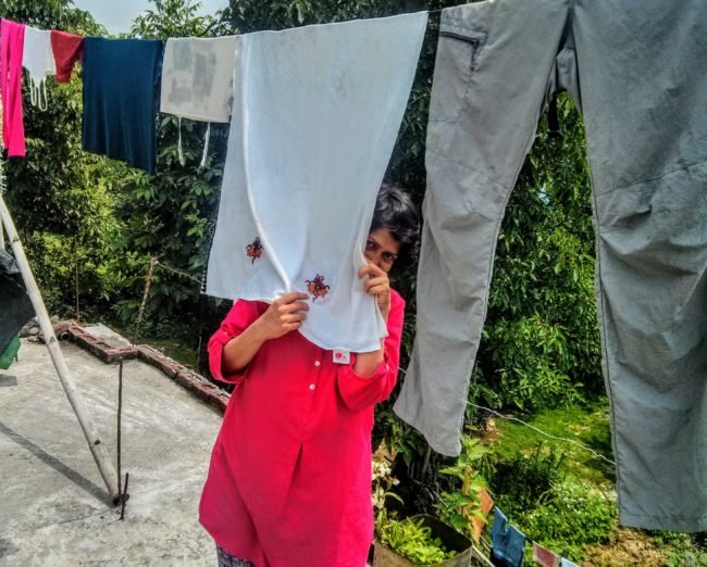 A woman drying clothes on the clothesline of a terrace of home stay in Sarmoli