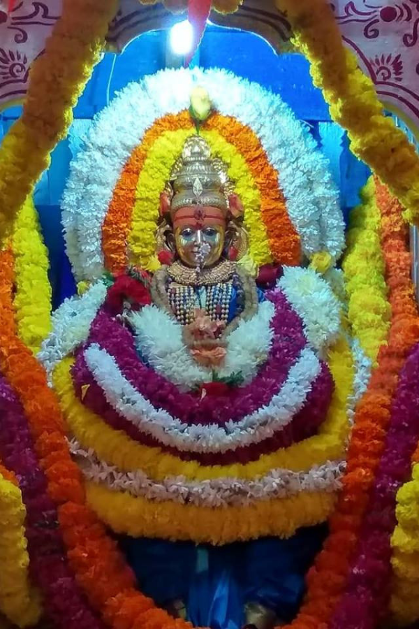 Main deity idol of Goddess Shantadurga flanked by Lord Vishnu and Lord Shiva inside the temple sanctum, beautifully decorated with garlands and traditional ornaments