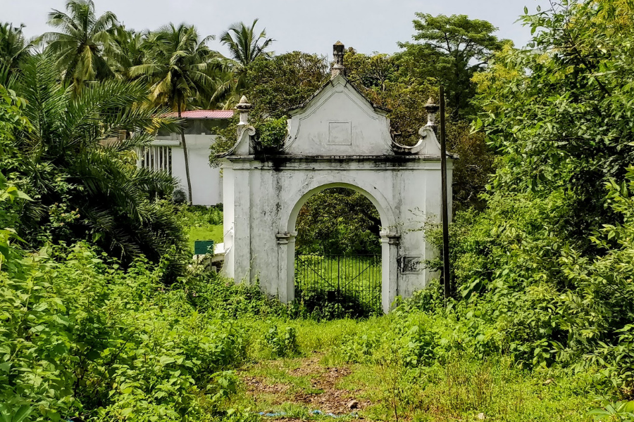 Historical ruins of the British Military Cemetery at Dona Paula showing weathered gravestones and remnants of the colonial-era burial ground among overgrown vegetation
