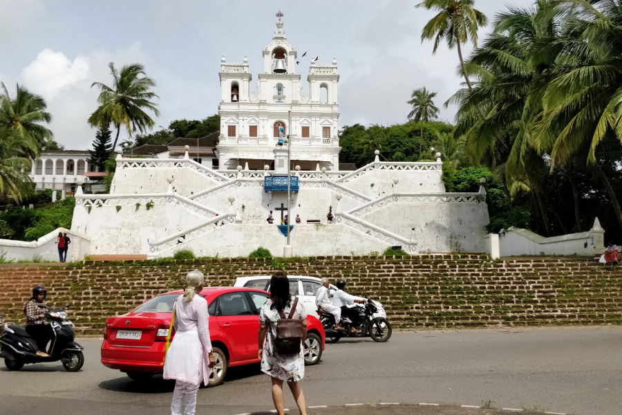 Iconic Our Lady of Immaculate Conception Church in Panaji with its distinctive zigzag baroque stairway, white facade, and twin bell towers against blue sky